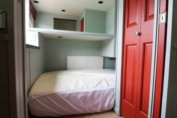 a bedroom with a bed a dresser and a door