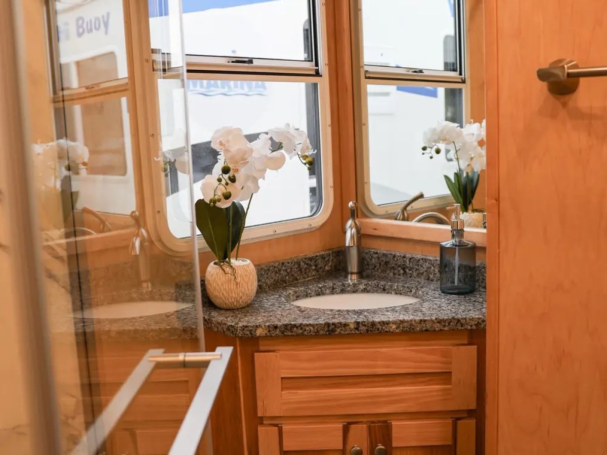 Wooden bathroom with granite counter, sink, flowers, and window.