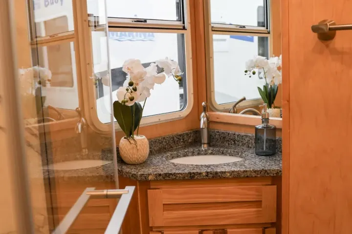 Wooden bathroom with granite counter, sink, flowers, and window.