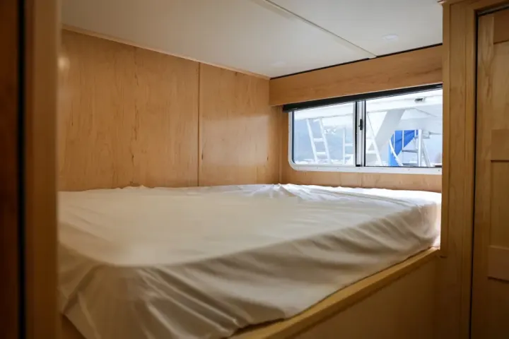 Compact wooden bedroom with a neatly made bed and a window.