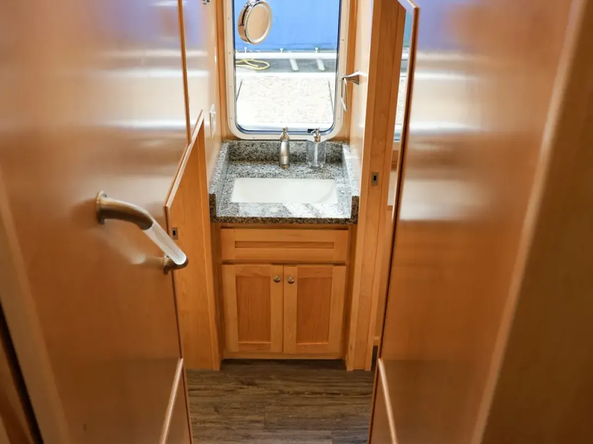 Wooden stairs leading to a sink below a window with a view of a boat.