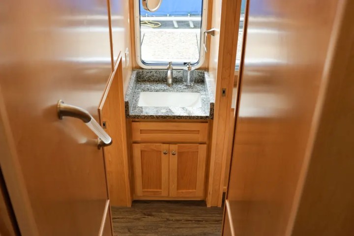 Wooden stairs leading to a sink below a window with a view of a boat.