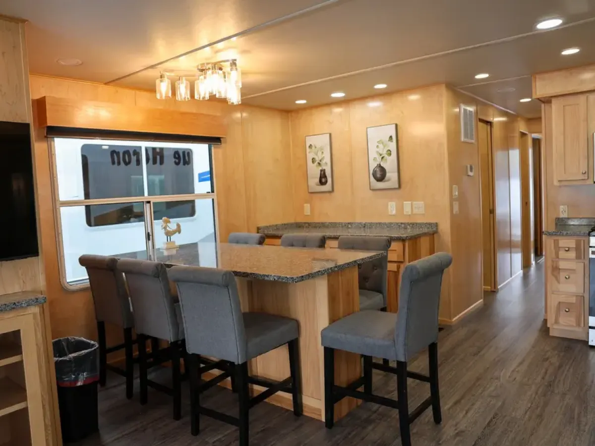 Modern RV interior with dining area, gray chairs, and built-in kitchen cabinets.