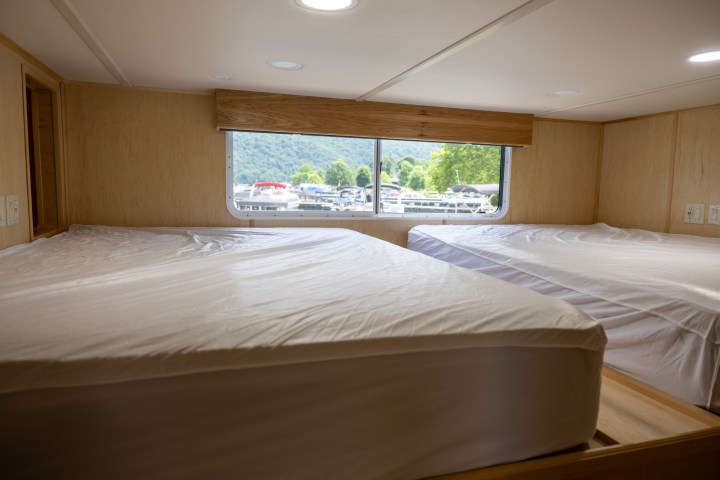 Cabin interior with two beds and a window view of boats on water.