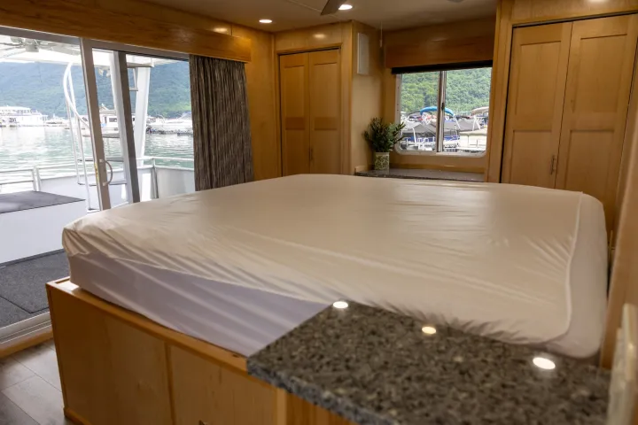 Bedroom with large bed and view of marina through glass doors.