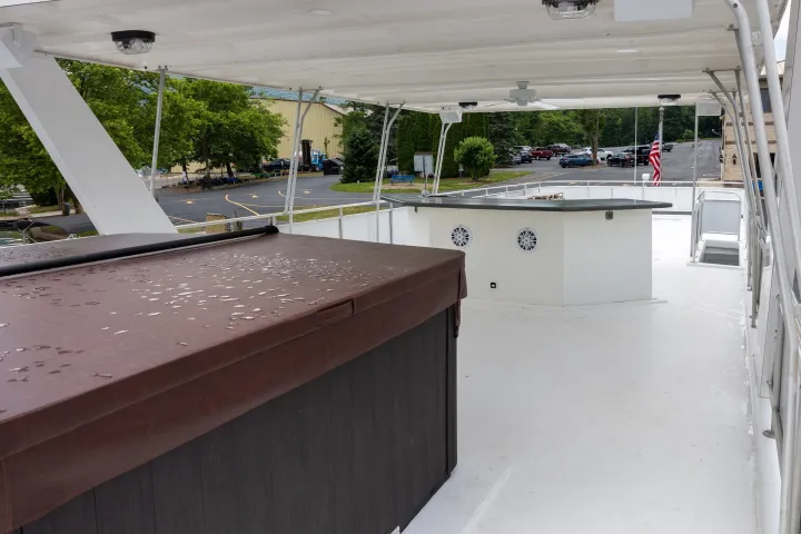 Covered rooftop deck with hot tub and bar under a canopy.