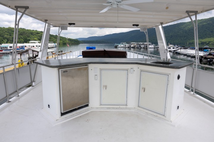 Boat deck with bar counter overlooking a marina and mountains.