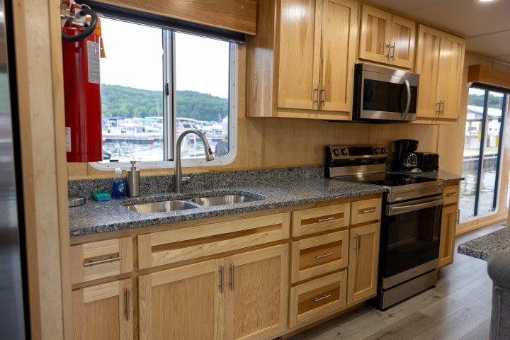 Modern kitchen in a houseboat with wood cabinets and stainless steel appliances.