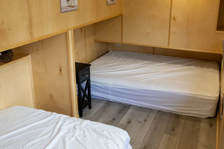Two twin beds in a wood-paneled room with wall art.